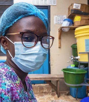 A closeup shot of a young black female wearing a hairnet and a medical face mask